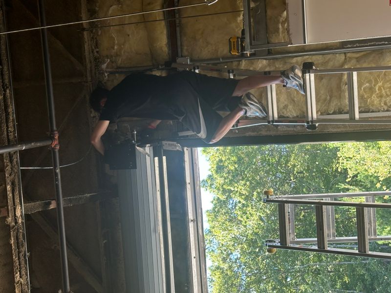 Technician installing commercial overhead door from ladder in warehouse