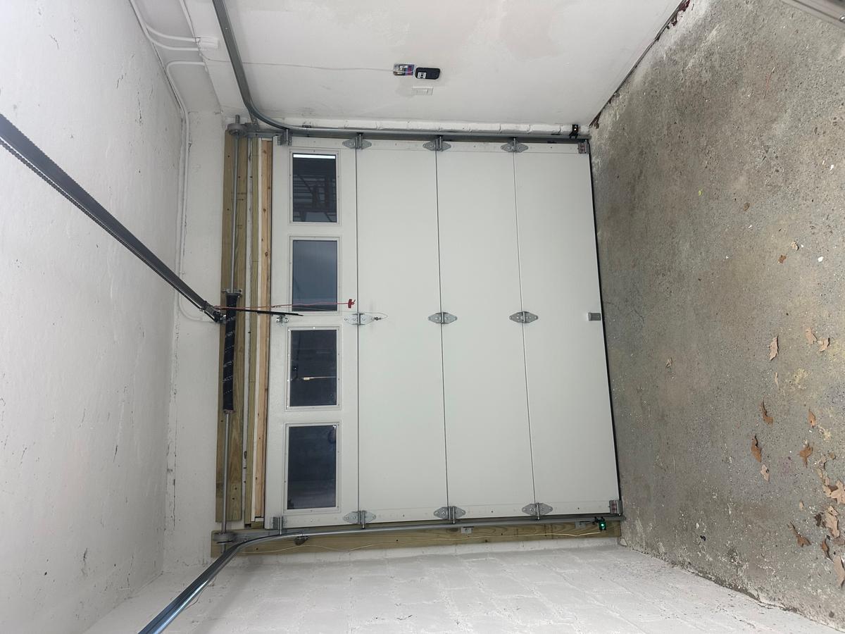 Interior view of newly installed white sectional garage door with vertical window inserts