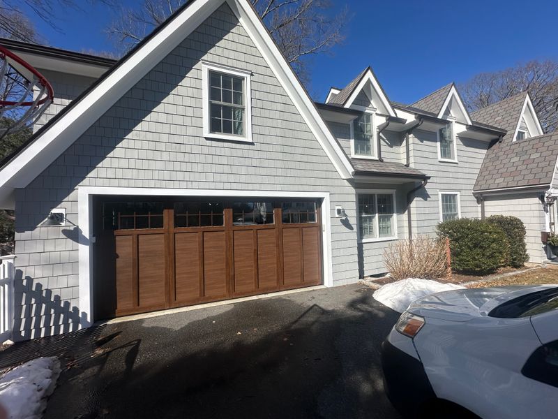 Wide angle of craftsman wood garage door installed on gray colonial home